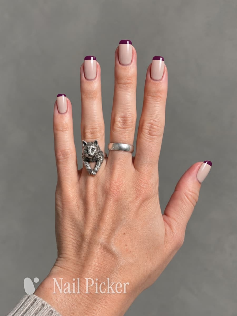 The same hand, this time a French tip — a nude base with a deep burgundy edge on every nail.