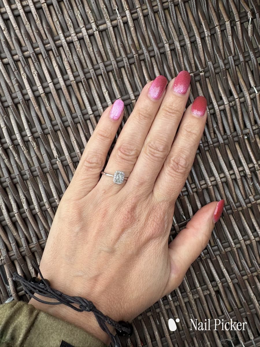 The same hand once more, nails in a pink glitter that runs from bright pink to deep rose.