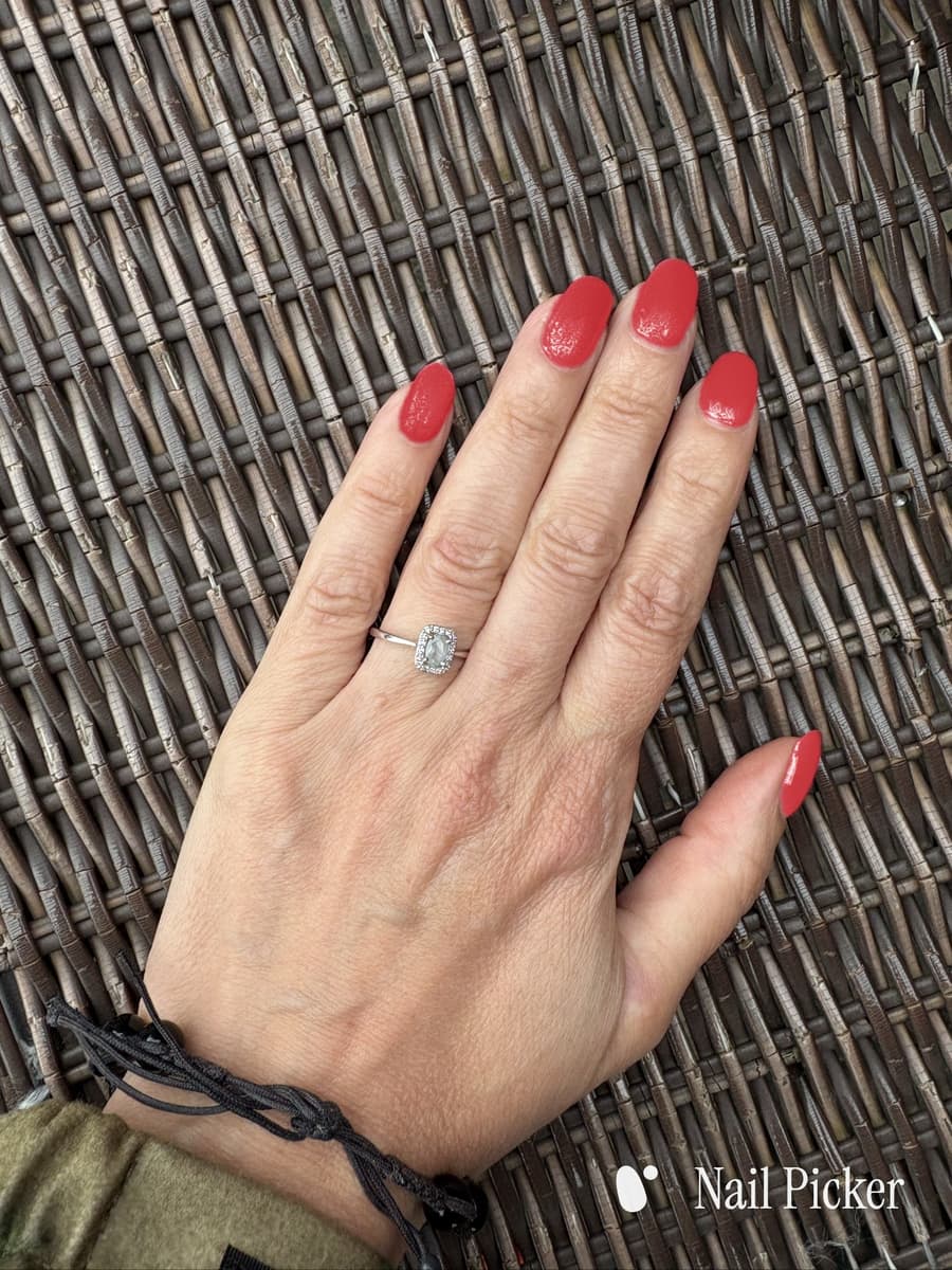 The same hand and the same pose, nails in a bright pillar-box red.